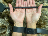 Two hands holding a black leather strap against a fur background